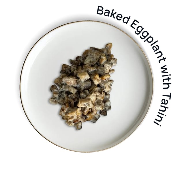 Baked eggplant with tahini on a white plate with a gold rim, viewed from above.