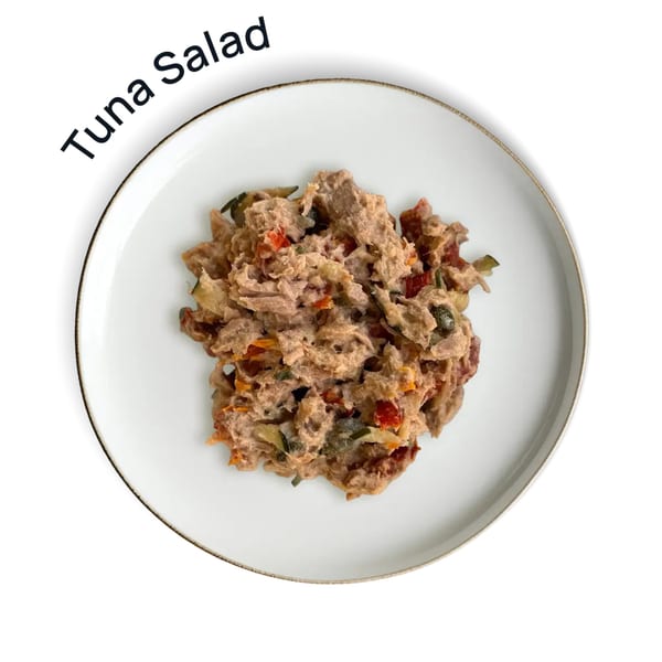 Overhead view of a white plate with a serving of tuna salad mixed with vegetables.