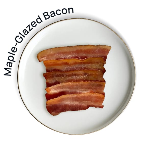 Several strips of maple-glazed bacon are neatly stacked on a white plate with a gold rim.