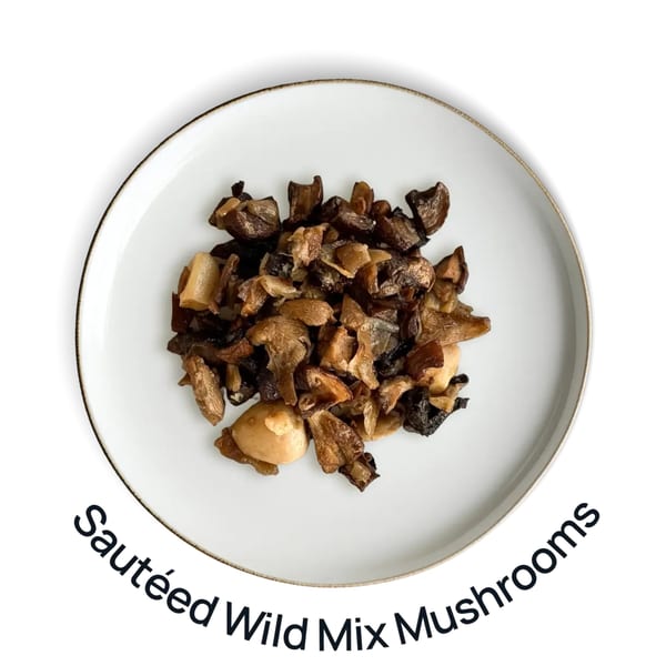 A white plate with a gold rim holds a serving of sautéed wild mix mushrooms.