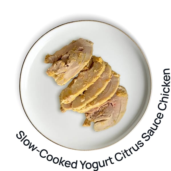 Overhead view of sliced slow-cooked yogurt citrus chicken on a white plate with a gold rim.
